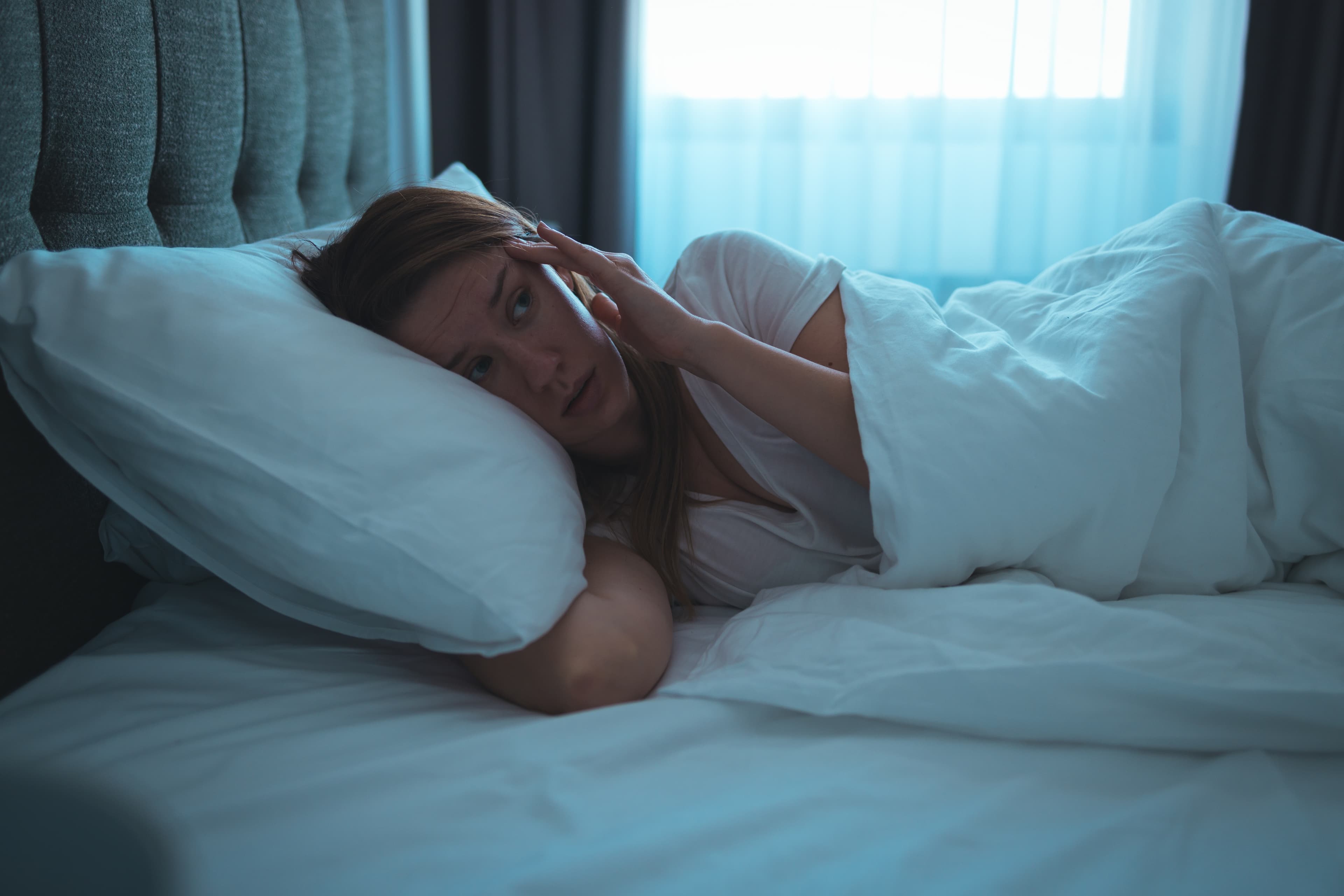 A lady lying in bed awake as she experiences from insomnia