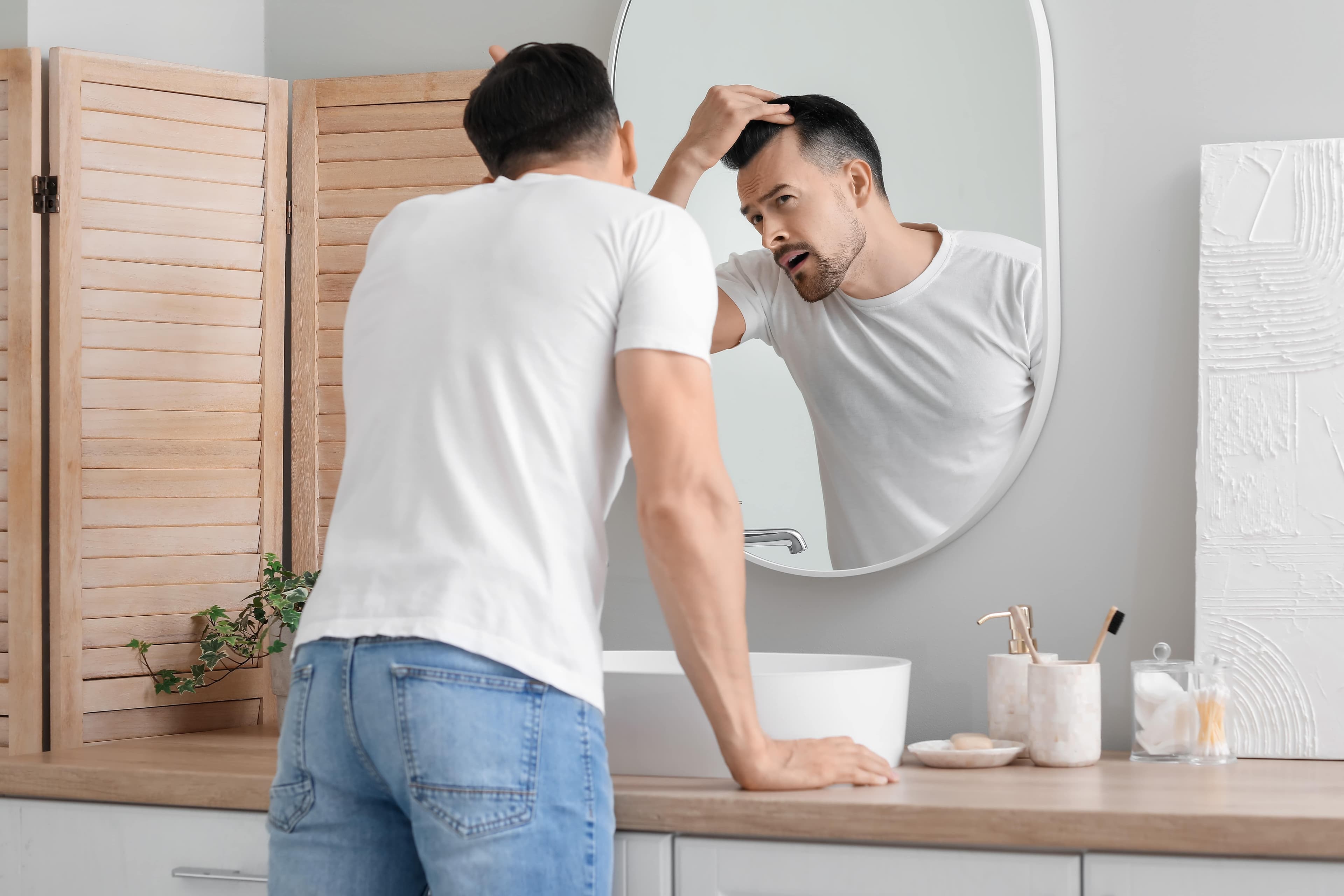 A man looking into the mirror assessing himself