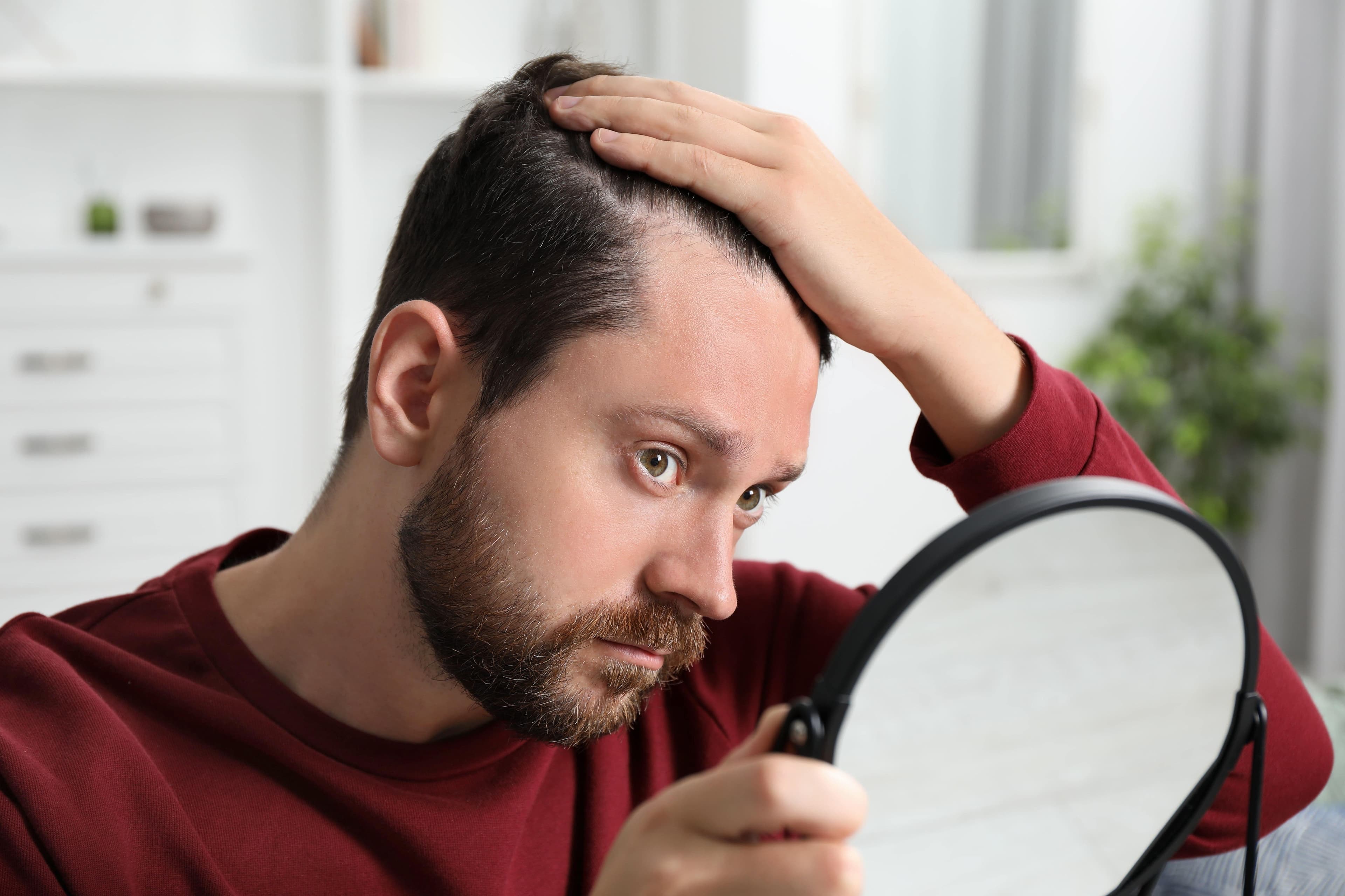 A man checking his hairline in the mirror