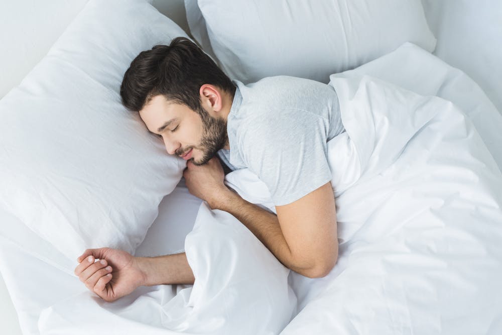A sleeping man holding a pillow.