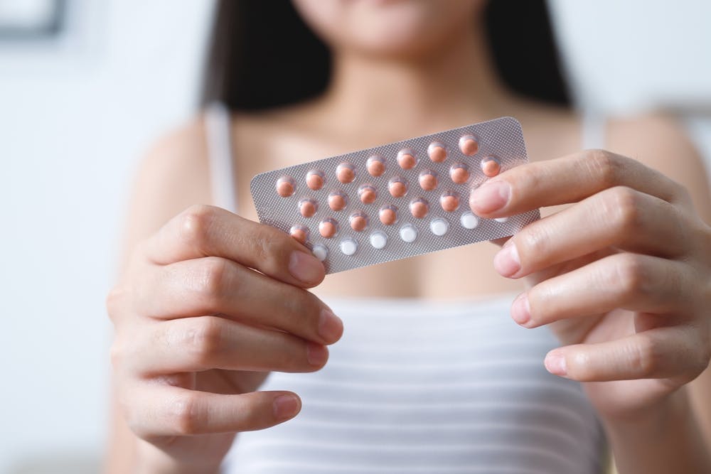 A lady holding up a pack of the contraceptive pill